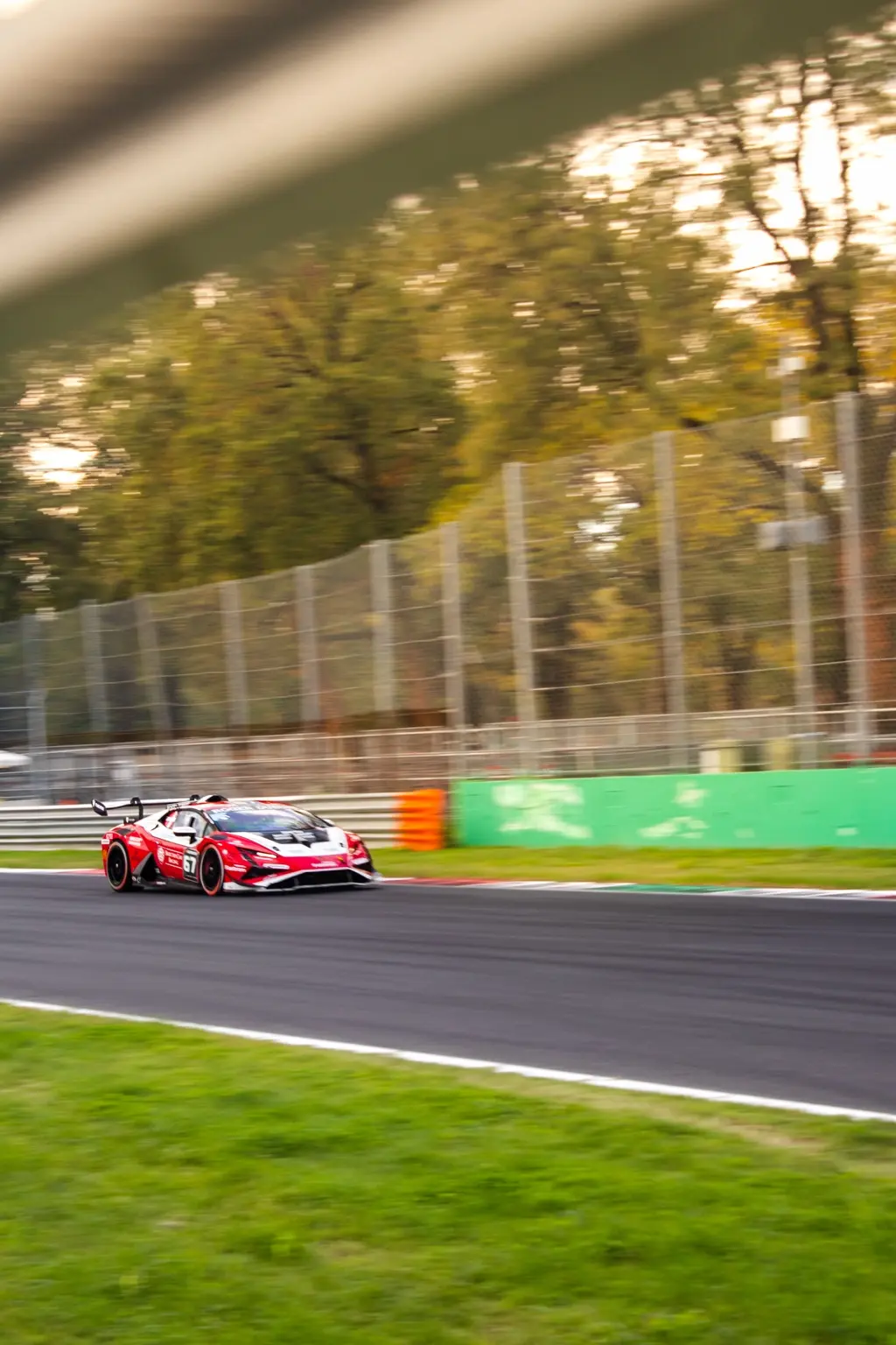 Red and white GT racing car at speed in warm evening light