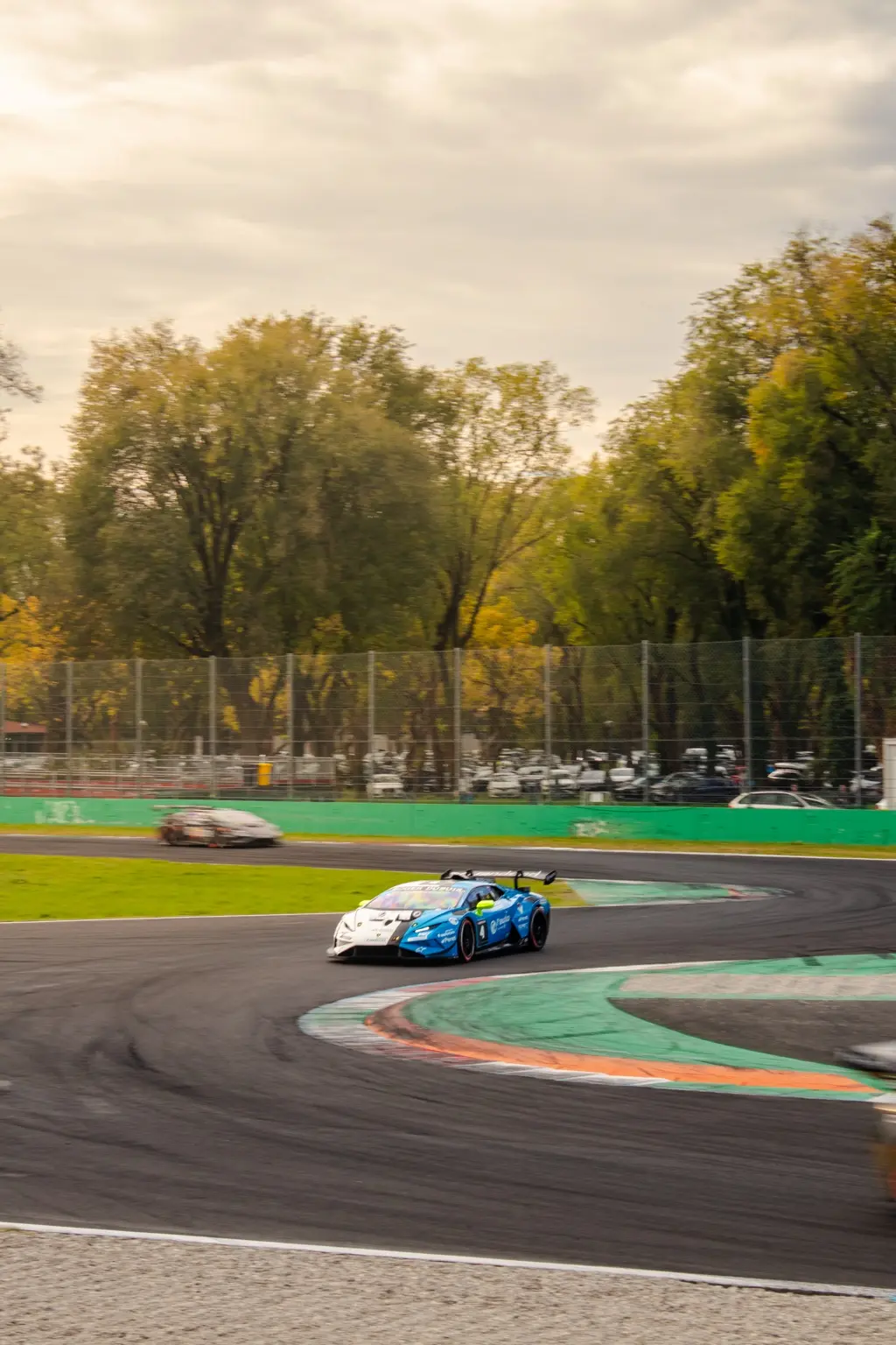 Blue and white Lamborghini race car chasing another car through a corner